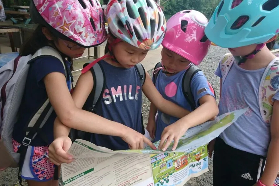 Children in helmets examining a map outdoors