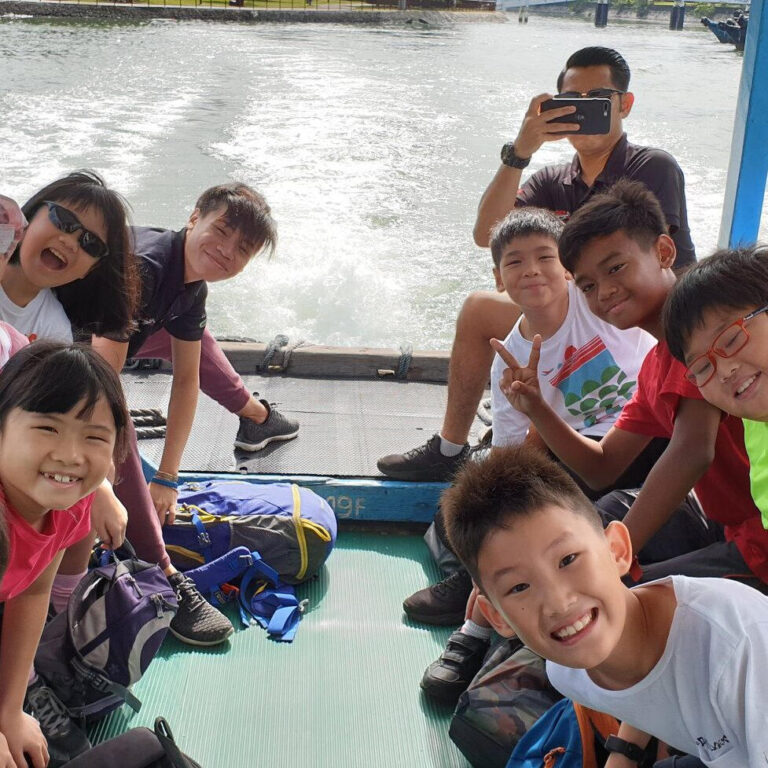Group of children smiling on a boat, enjoying a day out on the water